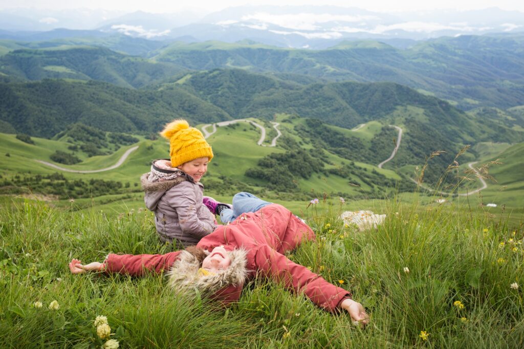 happy children are sitting on background of nature - mountain landscape. travel with kids